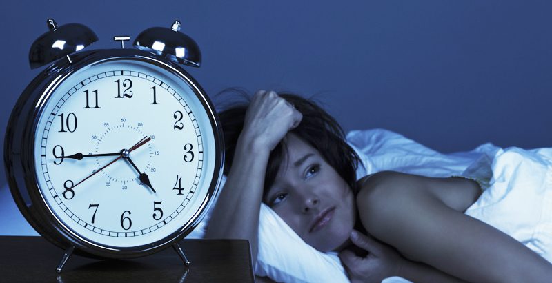 carolina-cardiology-associates-woman-lying-in-bed-with-clock